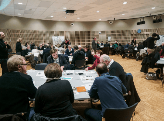 Réunion de différentes personnes autour de tables pour échanger.